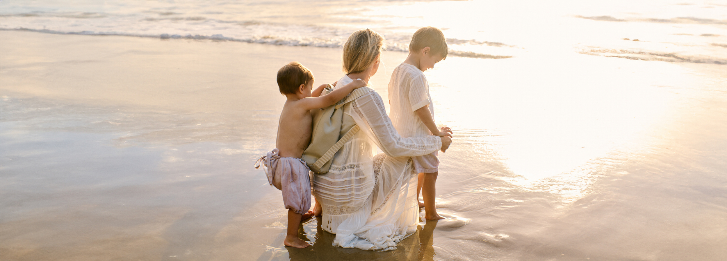 Mother Laura King with her children holding H Bag as a backpack at the beach