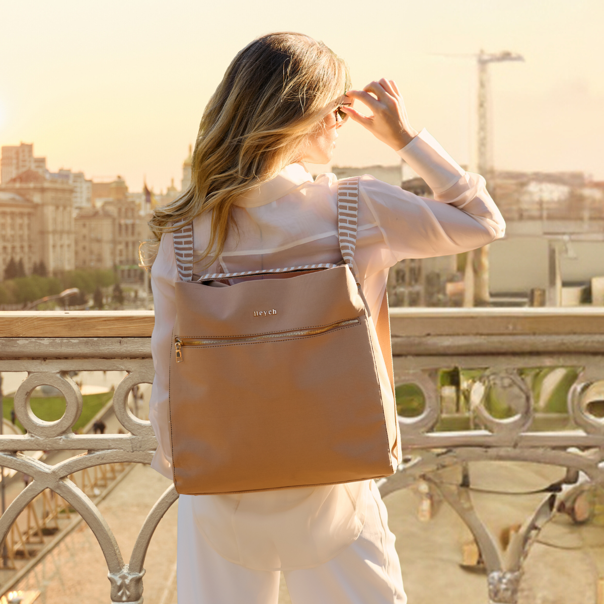 Woman carrying Tan neoprene tote back converted to a backpack